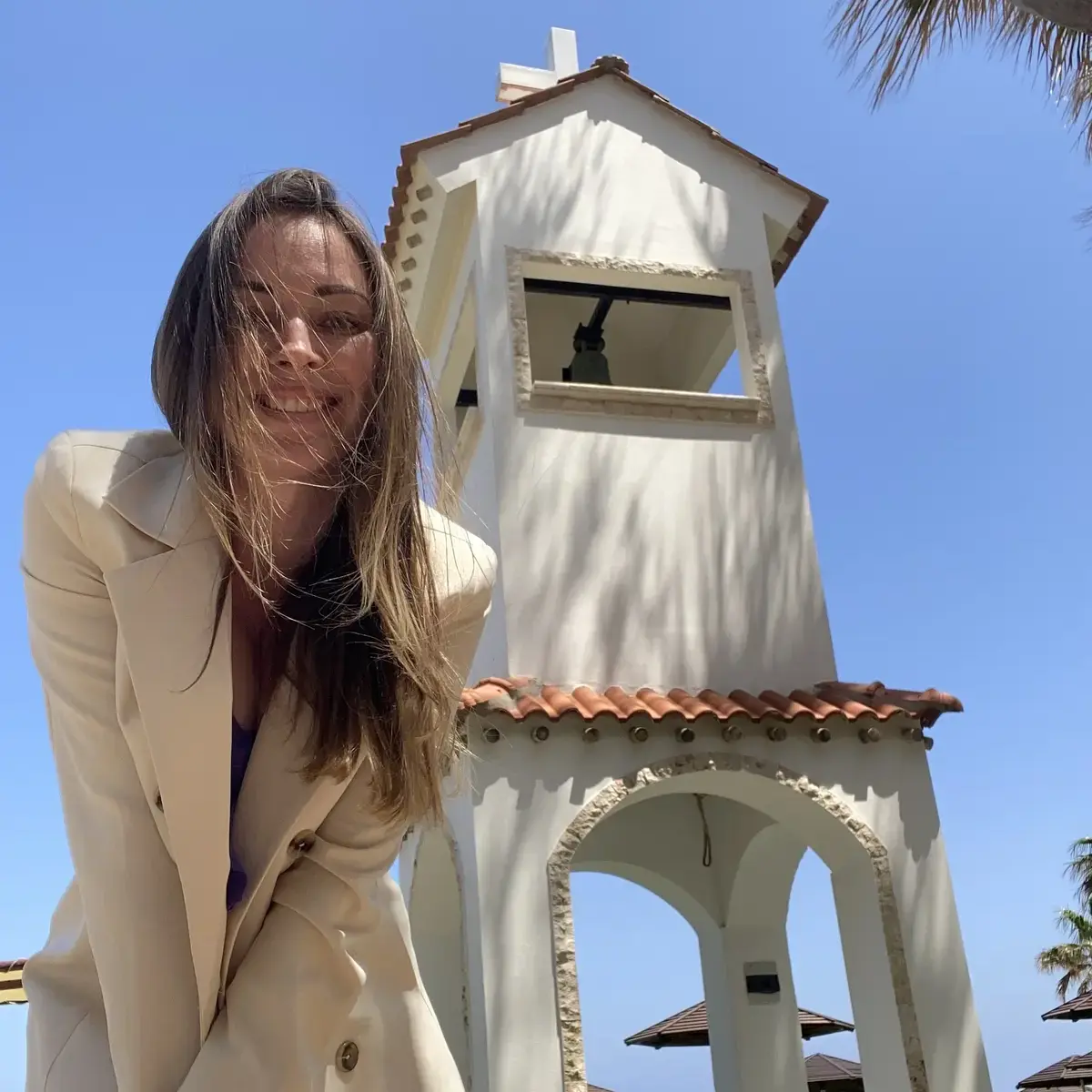 Smiling girl in a beige jacket in front of the chapel